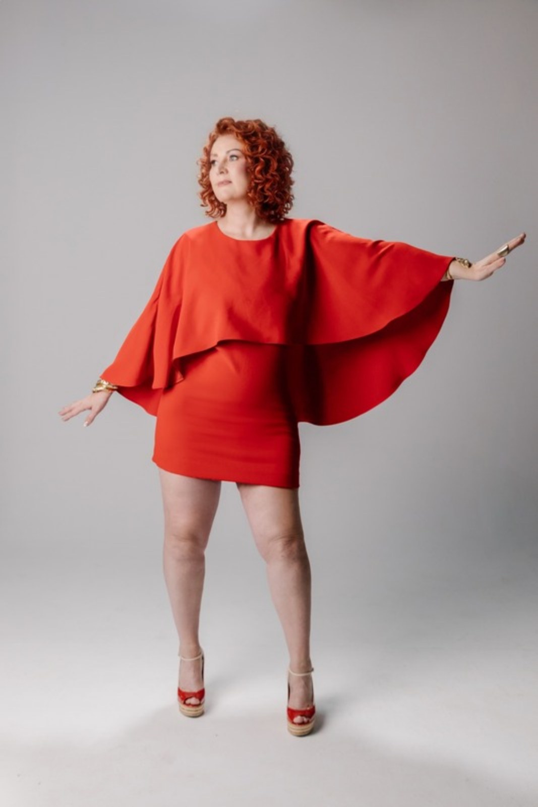 Kelly Diels, red hair, in a red cape dress